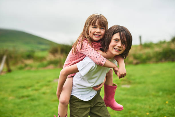 They have the most fun when they play together Portrait of a little boy giving his sister a piggyback ride outdoors ireland photos stock pictures, royalty-free photos & images