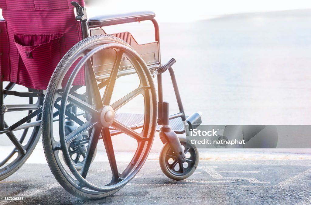 cerrar vista de silla de ruedas vacía con símbolo de handicap de pavimento - Foto de stock de Silla de ruedas libre de derechos