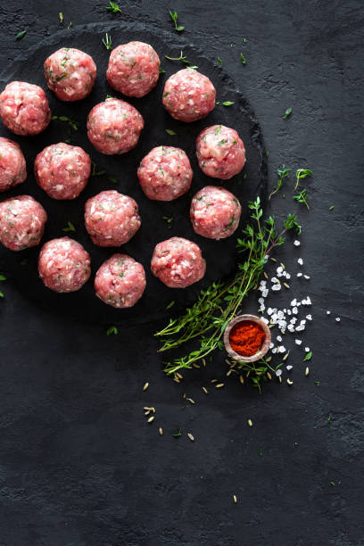 istock Raw meatballs on dark background, top view 887209182