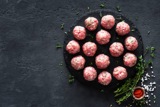 istock Raw meatballs on dark background, top view 887209184