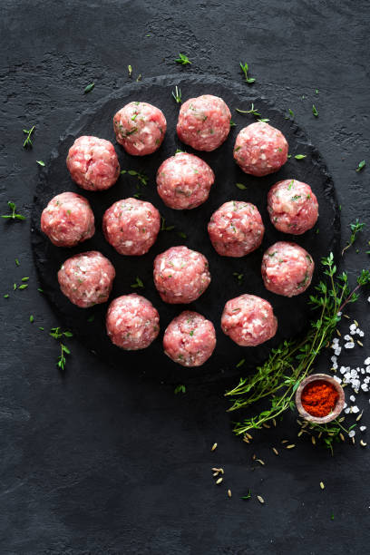 istock Raw meatballs on dark background, top view 887209186