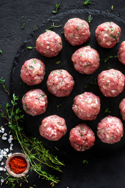 istock Raw meatballs on dark background, top view 887209386
