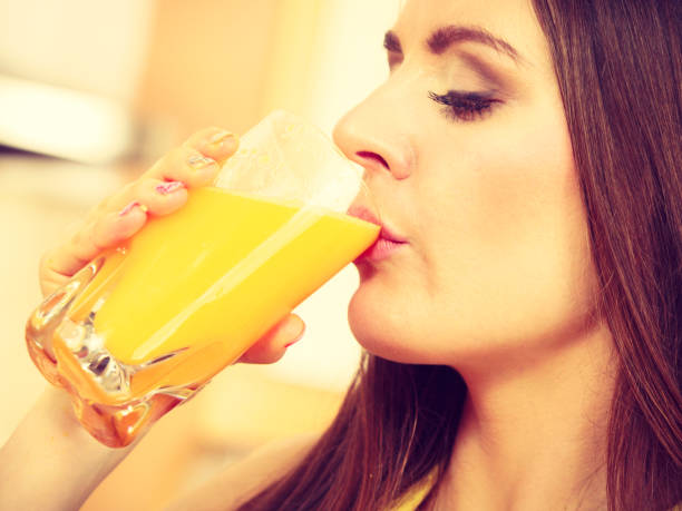 istock Woman in kitchen drinking fresh orange juice 887227120