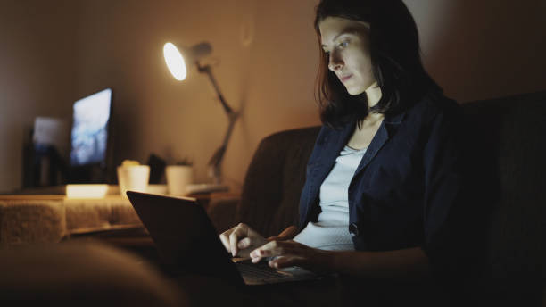istock Young concentrated woman working at night using laptop computer and typing message 887239488