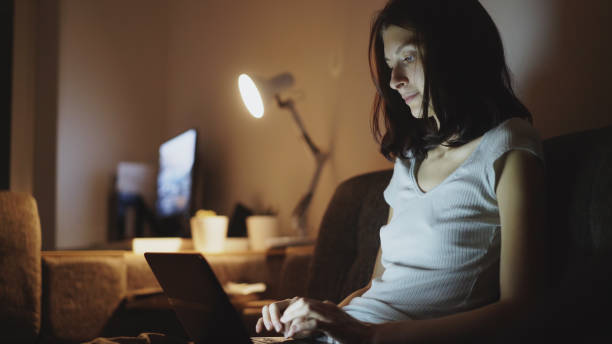 istock Young attractive woman sharing social media using on laptop computer at home in night time 887239630