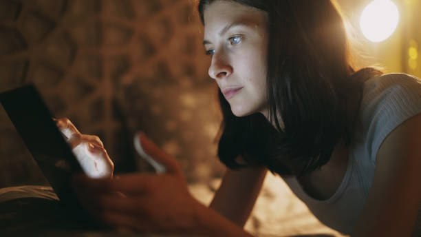 istock Young woman using tablet computer becuause of internet addiction and insomnia lying on bed at home at late night 887240430