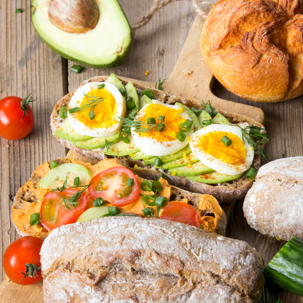 Sandwiches with avocado, eggs and tomato on a wooden background. Fresh organic vegetables, eggs and whole wheat bread. Healthy breakfast. Retro style.