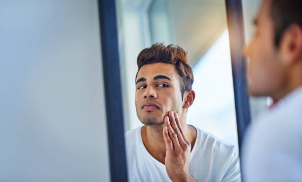 You don't get smoother than that Shot of a handsome young man admiring looking at his face in the bathroom mirror shaving stock pictures, royalty-free photos & images