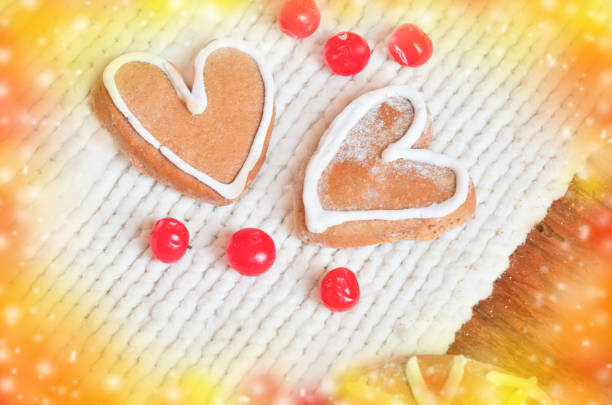 Love concept with red berries out in the form of heart  and  cookies in the form of heart  on a white tied background. Ripe red berries  and  cakes on a wooden background