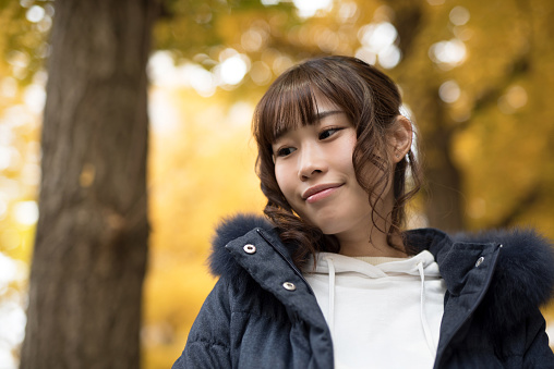 Young woman's portrait in the beautiful autumn leaves field in Tokyo, Japan, photographed naturally without heavy processing