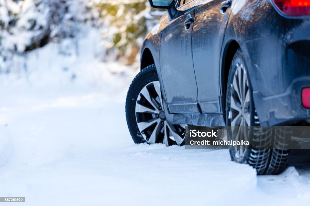 Winter tires. Black SUV car rear view on snowy forest road. Winter conditions. Car Stock Photo