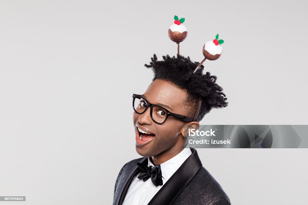Funny portrait of excited elegant man wearing christmas headband Funny portrait of happy elegant young man wearing Christmas headband. Man wearing jacket and bow tie laughing against white background. 25-29 Years Stock Photo