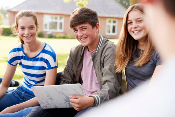 istock Teenage Students Sitting Outdoors And Working On Project 887302120