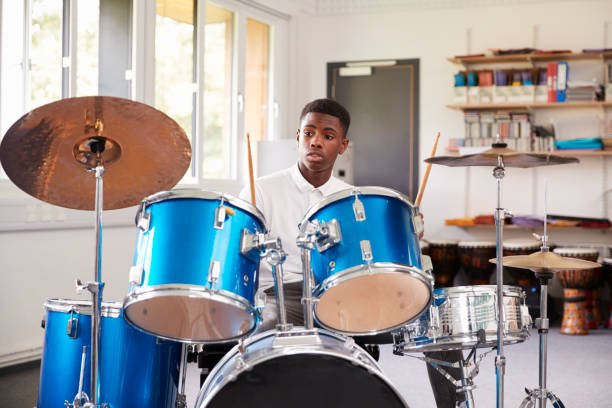 alumno adolescente masculino tocando la batería en la lección de música - baterias musicales fotografías e imágenes de stock