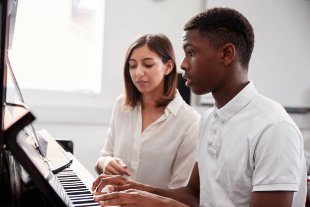 männliche schüler mit lehrer im musikunterricht klavier zu spielen - practicing piano child playing stock-fotos und bilder