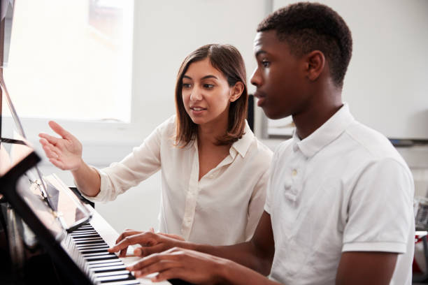 male pupil with teacher playing piano in music lesson - practicing piano child playing imagens e fotografias de stock