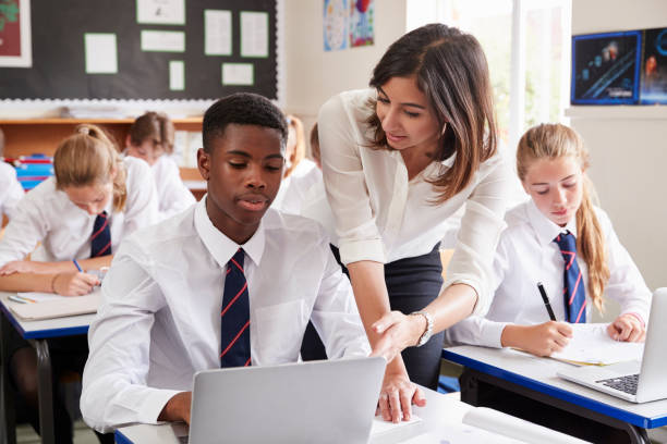 nauczycielka pomagająca uczniowi w korzystaniu z komputera w klasie - teacher computer high school student classroom zdjęcia i obrazy z banku zdjęć