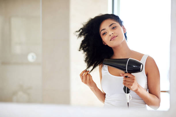 She puts a lot of love into her hair Shot of a young woman drying her hair in the bathroom blow drying stock pictures, royalty-free photos & images