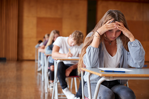 Estudiante adolescente ansioso sentado examinación en pasillo de la escuela photo