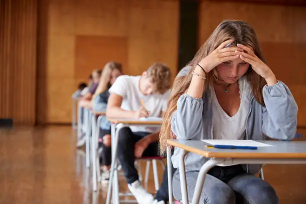 Photo of Anxious Teenage Student Sitting Examination In School Hall
