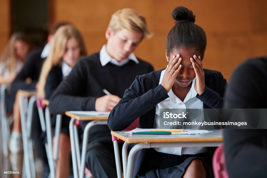 Estudiante adolescente ansioso sentado examinación en pasillo de la escuela - Foto de stock de Examen libre de derechos