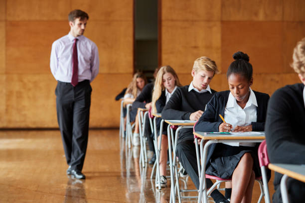 teenage étudiants assis examen avec professeur surveillant - exam photos et images de collection