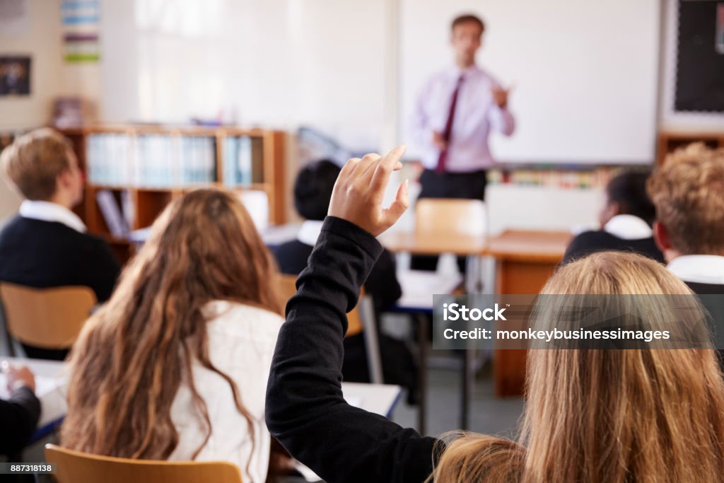 Studentessa che alza la mano per fare domande in classe - Foto stock royalty-free di Aula