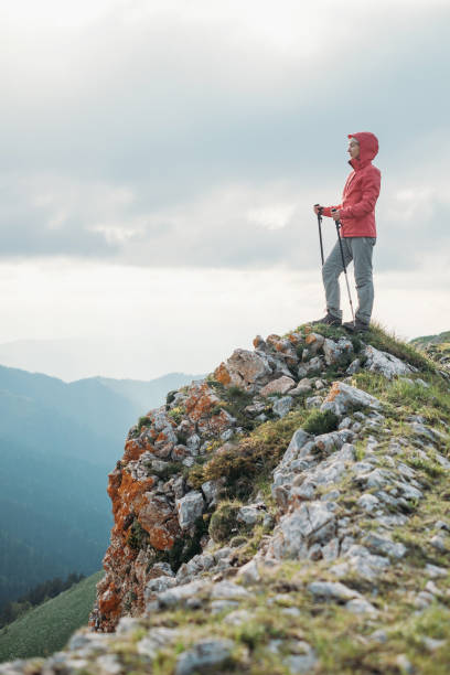 istock Female explorer standing on rock mountain. 887329764