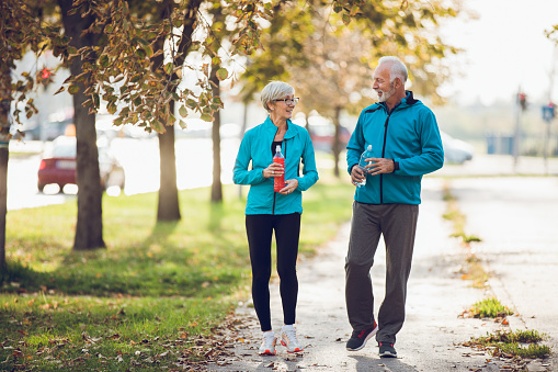 Mature couple walking together with water bottles. Copy space.