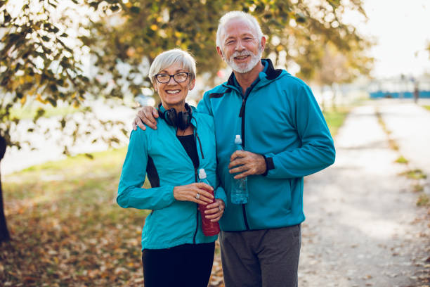 istock Smiling mature couple standing together with water bottles 887334388