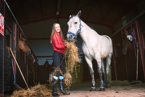 Shot of a teenage girl feeding her horse some hay