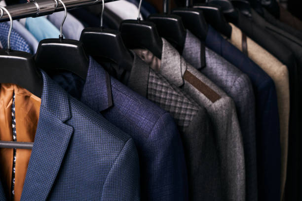 Mens suits on hangers in different colors Mens suits in different colors hanging on hanger in a retail clothes store, close-up mens fashion stock pictures, royalty-free photos & images
