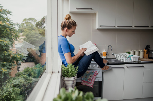 Young female reading in the kitchen.