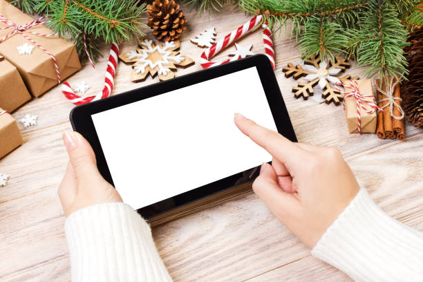 istock Tablet computer in girl hands. tablet computer with red gift box, christmas candy and fir branches. Free space for text. top view. Copy space. Closeup 887390190