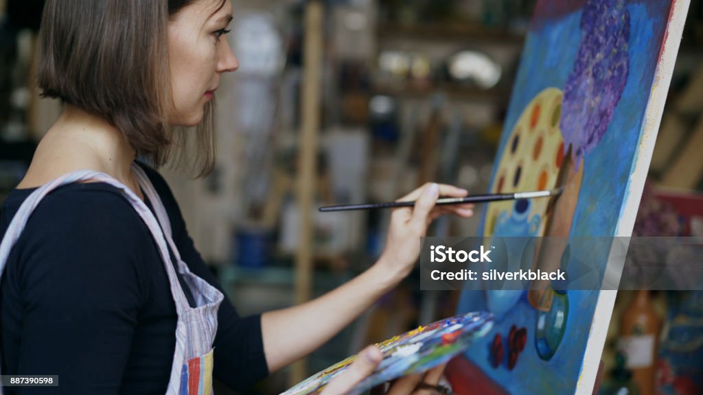 Young artist woman painting still life picture on canvas in art-school Young artist woman painting still life picture on canvas in art-school indoors Painting - Activity Stock Photo