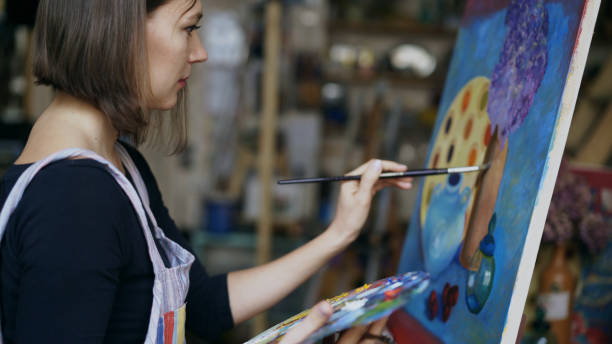 Young artist woman painting still life picture on canvas in art-school Young artist woman painting still life picture on canvas in art-school indoors art class photos stock pictures, royalty-free photos & images
