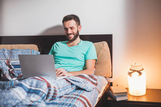 istock Young man lying in the bed working on a laptop 887406858