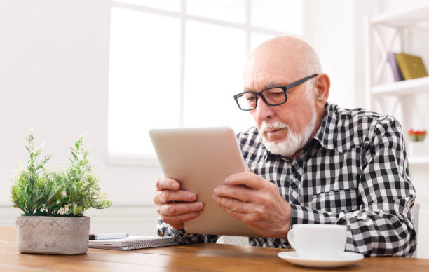 istock Senior man reading news on digital tablet 887406926