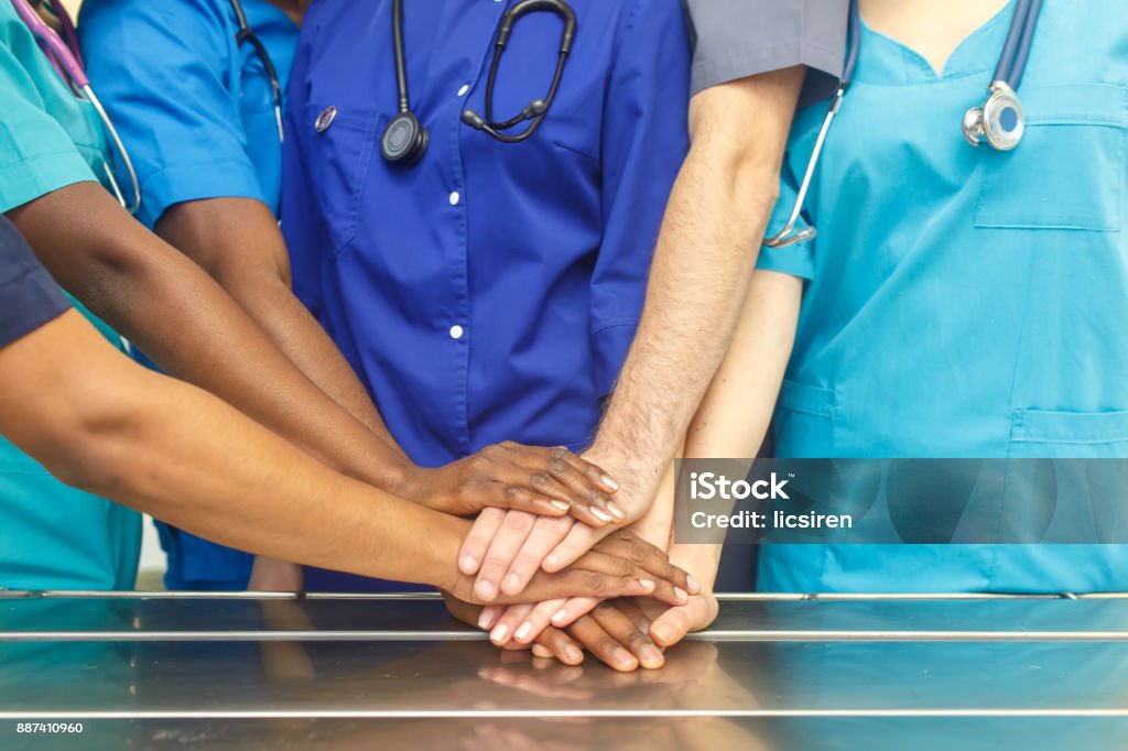 Multiracial team of young doctors stacking hands indoor, Group Of Multiracial Doctor surgery team stacking hands in a operating room, medical teamwork Multiracial Group Stock Photo
