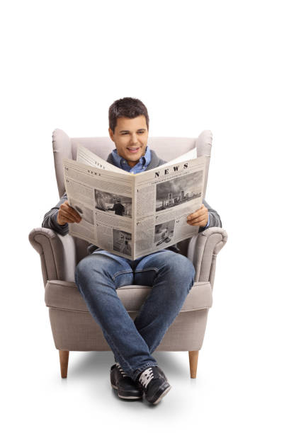 młody mężczyzna siedzący w fotelu i czytający gazetę - reading newspaper 30s adult zdjęcia i obrazy z banku zdjęć