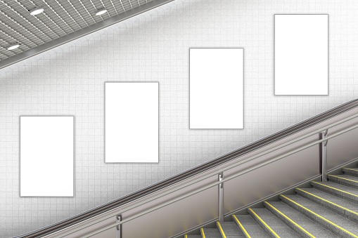 Four blank vertical advertising posters on wall of underground escalator. 3d illustration