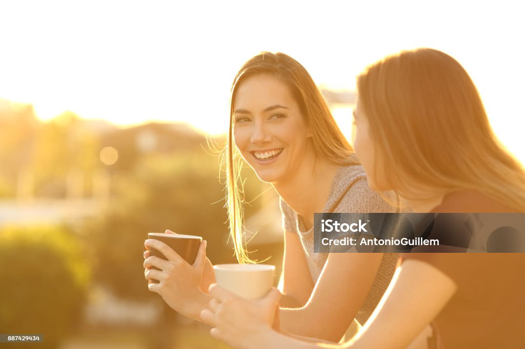 Deux amis heureux de parler dans un balcon au coucher du soleil - Photo de Balcon libre de droits