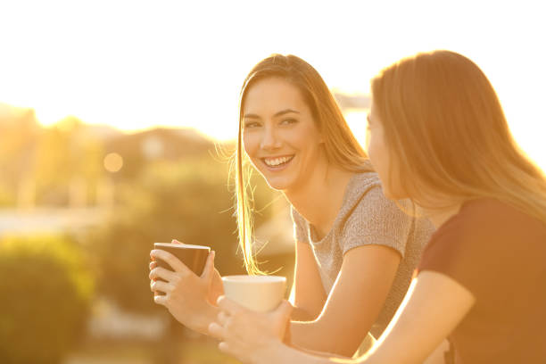 due amici felici che parlano in un balcone al tramonto - outdoors looking at camera little girls child foto e immagini stock