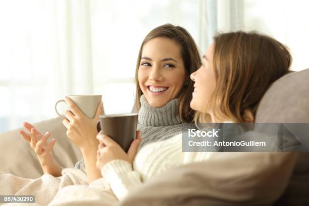 Two Roommates Talking On Couch In Winter Stock Photo - Download Image Now - Friendship, Discussion, Talking