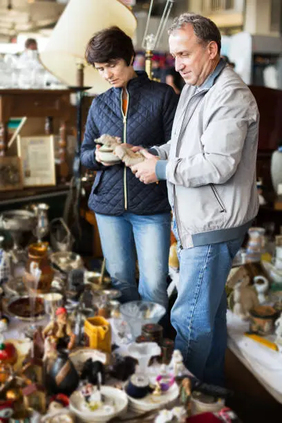 Adult woman and her husband are visiting the market of old things and shopping outdoors