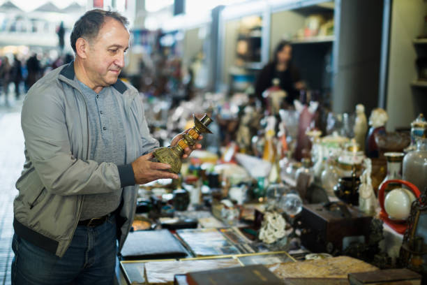 istock Senior man is looking ancient lamp at the fleamarket 887436492