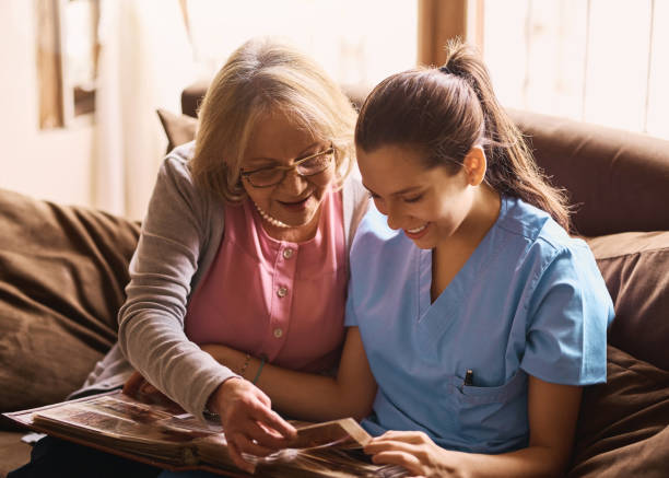 Stimulating memories through photographs Shot of a nurse and a senior woman looking at a photo album together nostalgia stock pictures, royalty-free photos & images