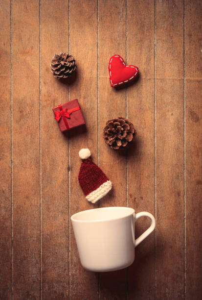 istock White cup and Christmas hat with gifts and pine cones 887440438