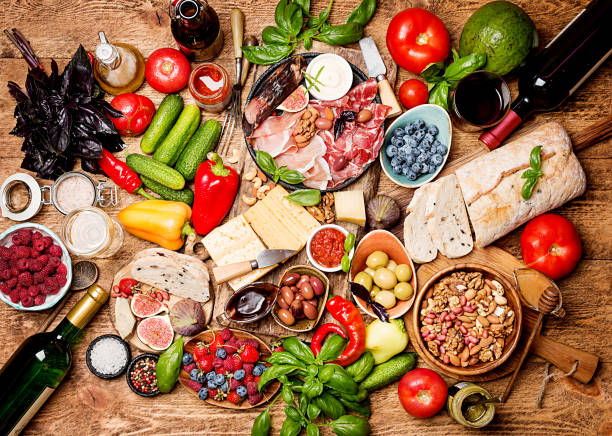 Top view table full of food Top view table full of food. Italian antipasti wine snacks set. Cheese variety, nuts, Mediterranean olives, sauces, Prosciutto di Parma or jamon, tomatoes, vegatables and berries and wine over wooden background mediterranean culture stock pictures, royalty-free photos & images