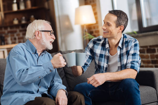 istock Cheerful elderly man clinking cups of tea with his son 887442416